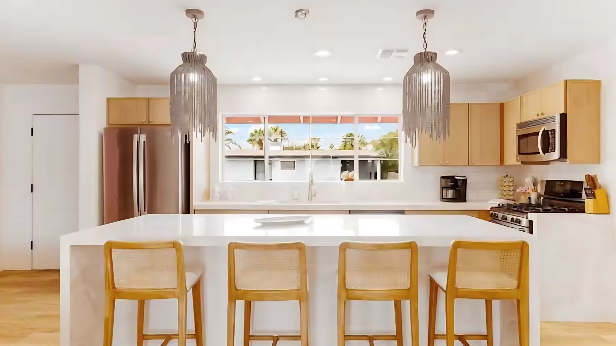 Warm wood kitchen cabinetry, woven pendant lights, and a white island at Cowgirl Cottage