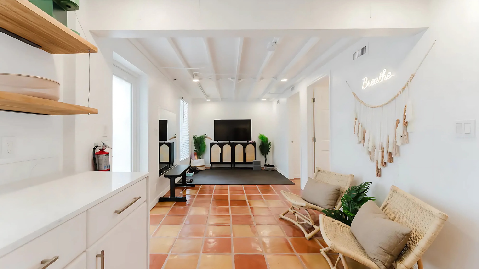 A light-filled sitting room with terracotta floors, cream seating, and natural wood at West Palm Oasis